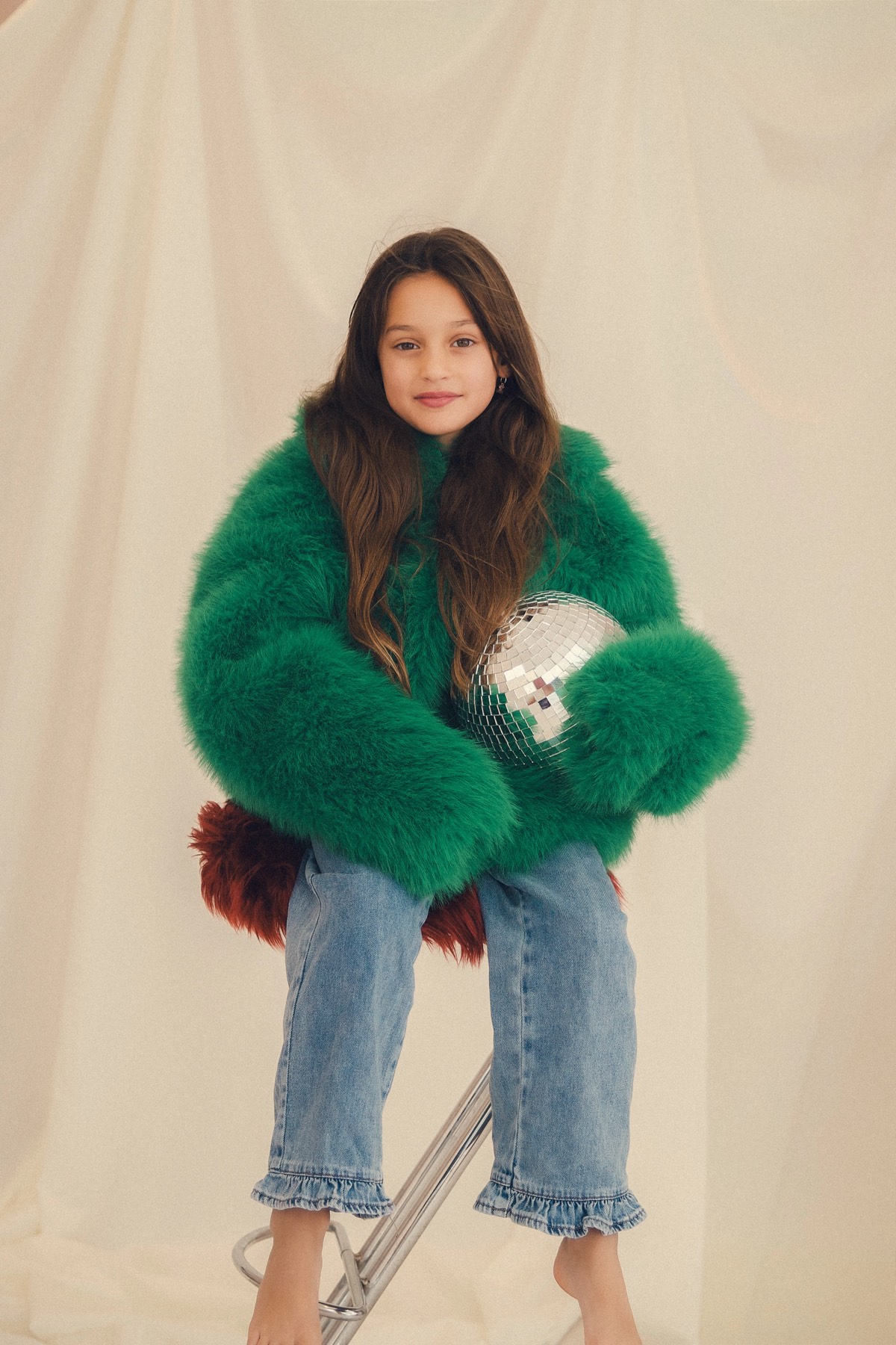 Meisje in een groene fluffy jas in de studio