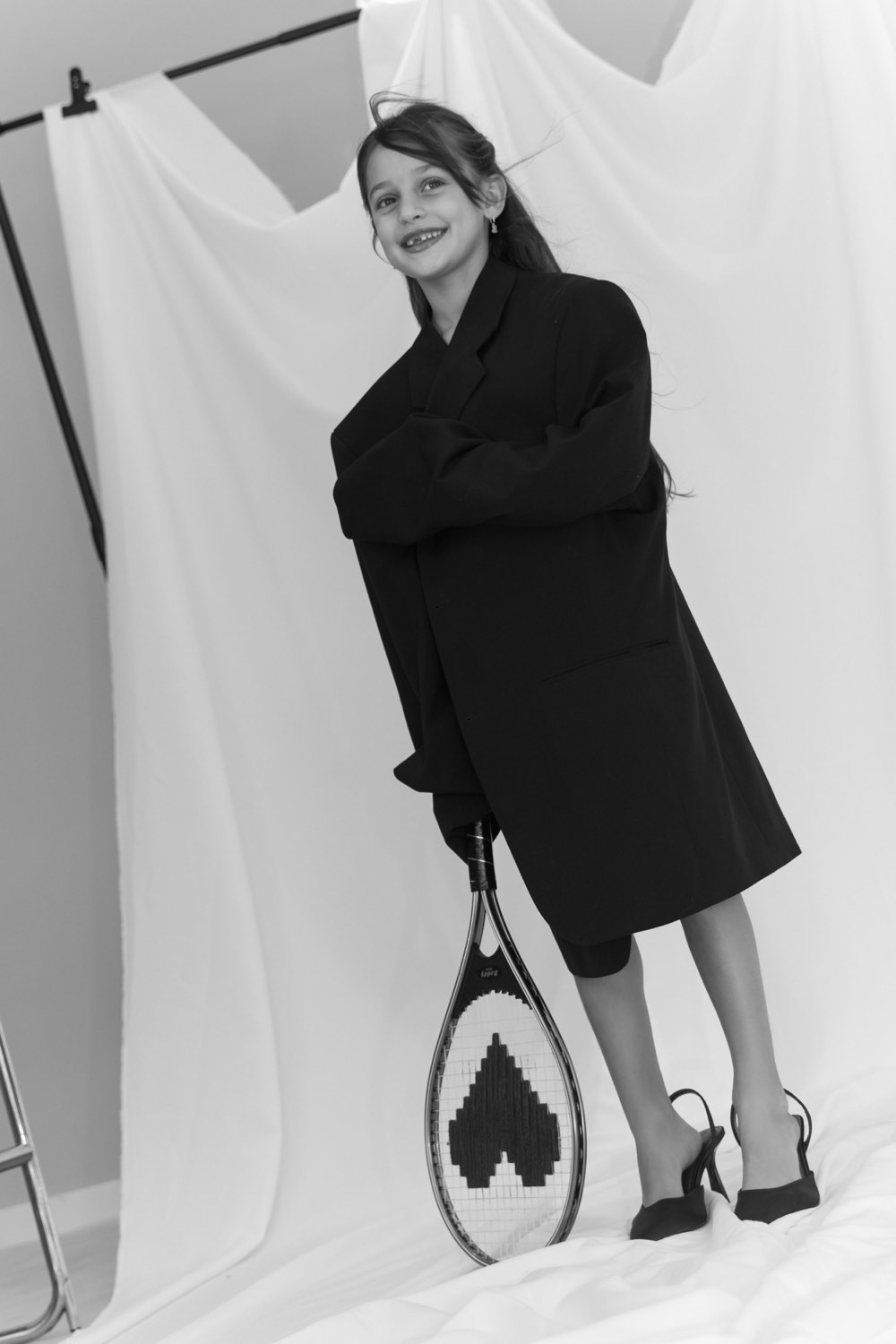 Meisje in een zwarte blazer met een tennisracket, zwart-wit