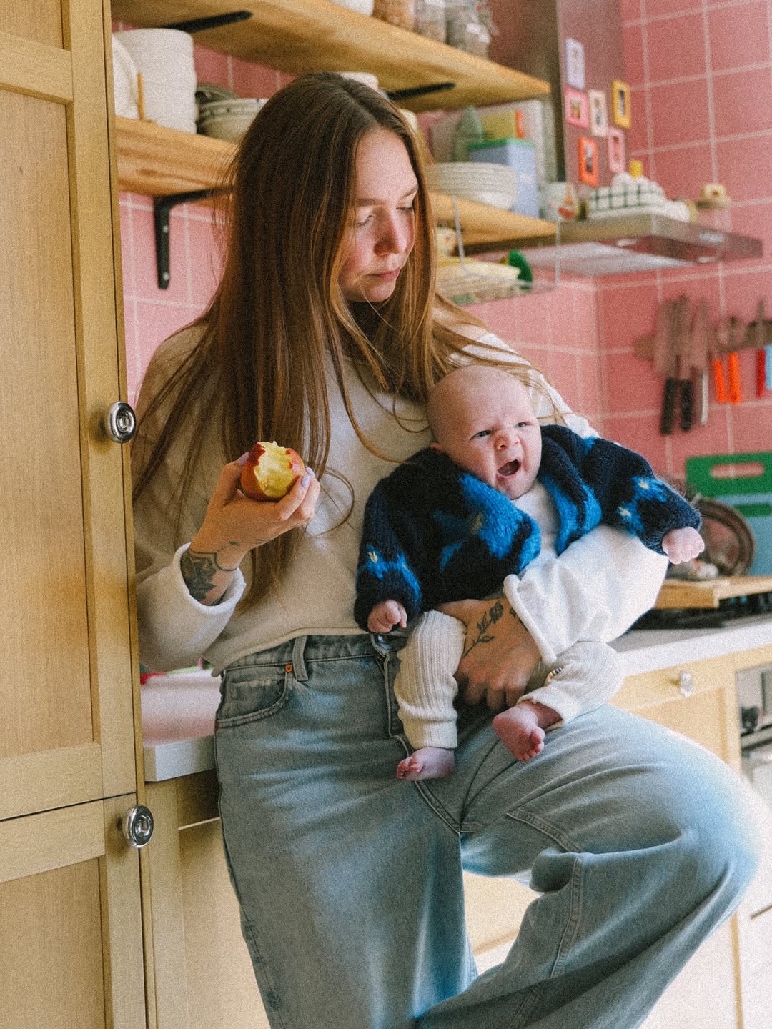 Moeder met haar baby op de arm in een roze keuken
