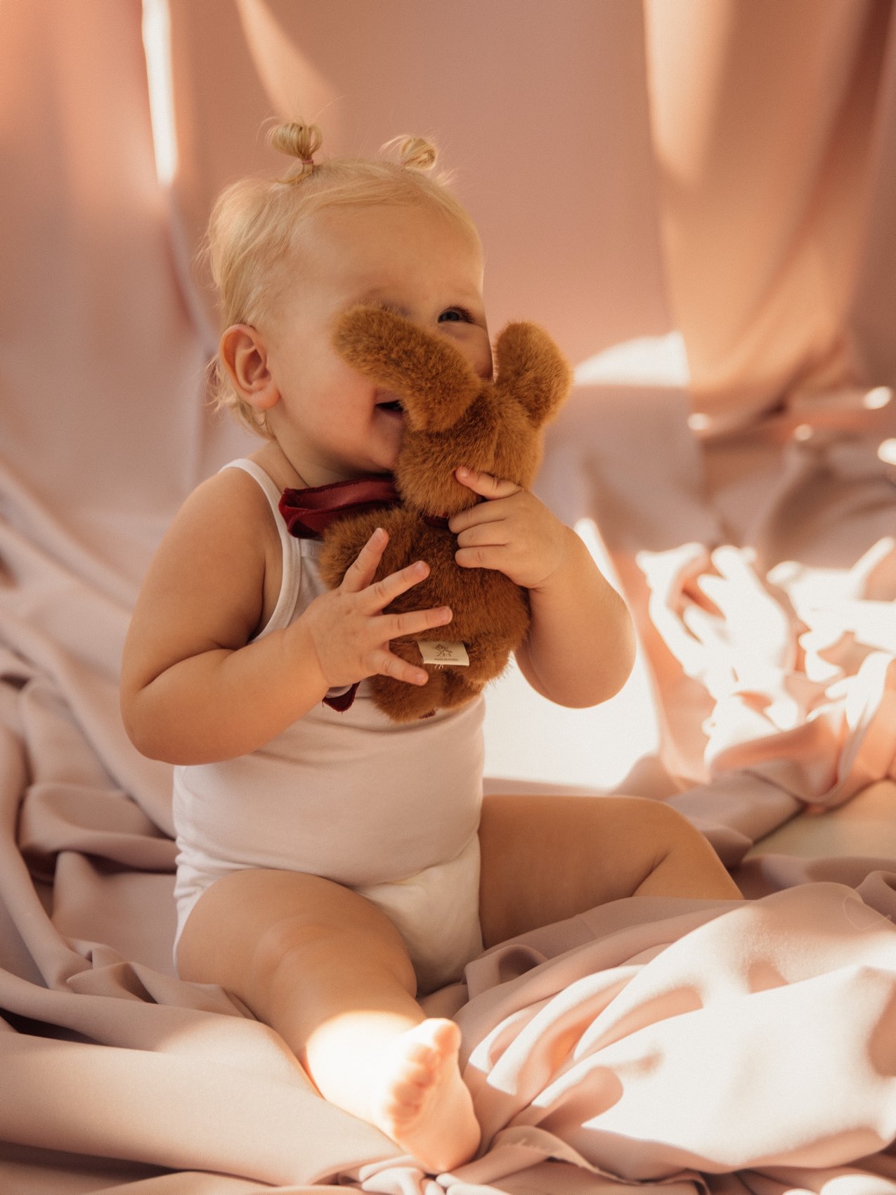 Baby met een teddybeer in het zonlicht